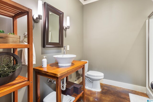 bathroom featuring sink, concrete floors, and toilet