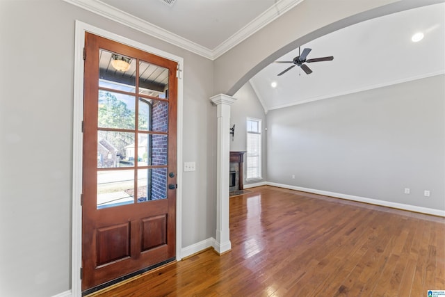 foyer featuring decorative columns, vaulted ceiling, ceiling fan, crown molding, and wood-type flooring