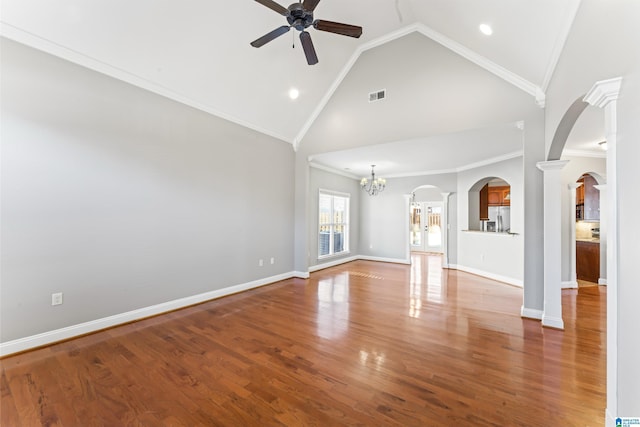 unfurnished living room with wood-type flooring, ceiling fan with notable chandelier, ornate columns, and crown molding