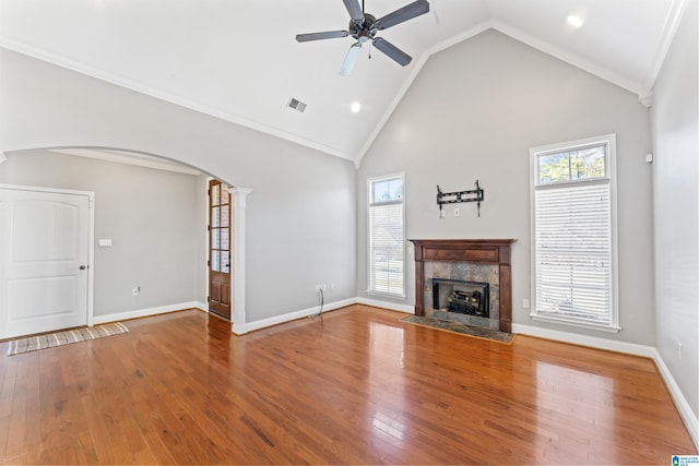 unfurnished living room featuring a tile fireplace, ceiling fan, high vaulted ceiling, decorative columns, and wood-type flooring