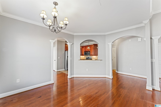 unfurnished living room with ornate columns, crown molding, hardwood / wood-style floors, and a chandelier