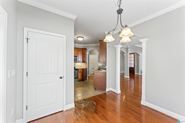 kitchen with hanging light fixtures, stainless steel appliances, a notable chandelier, backsplash, and crown molding