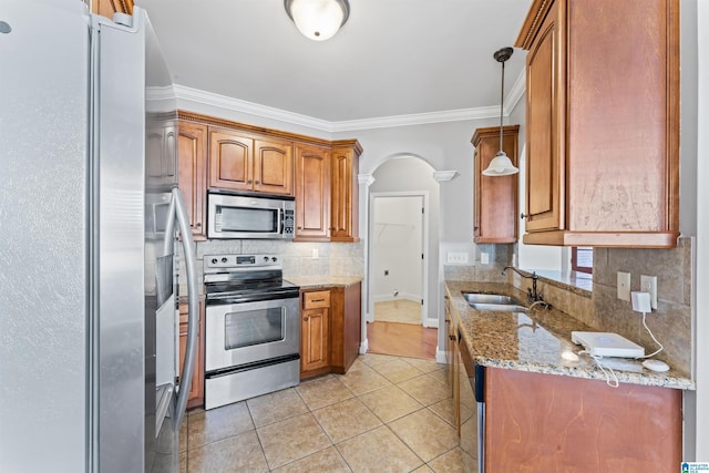 kitchen with light stone countertops, sink, decorative light fixtures, appliances with stainless steel finishes, and ornamental molding