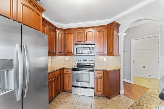 kitchen with light stone countertops, appliances with stainless steel finishes, and ornate columns