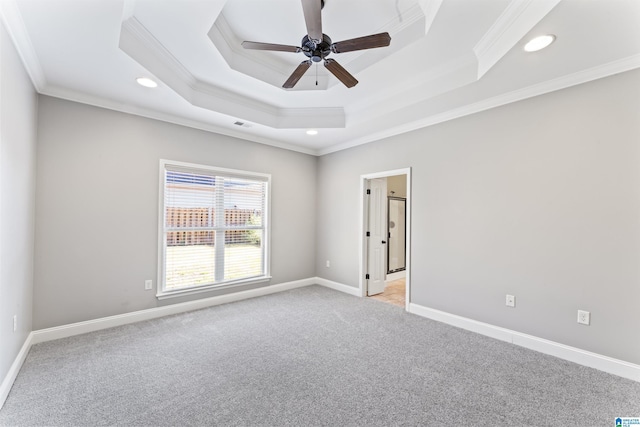 carpeted empty room with a tray ceiling, ceiling fan, and ornamental molding