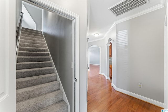 staircase featuring hardwood / wood-style floors, decorative columns, and crown molding