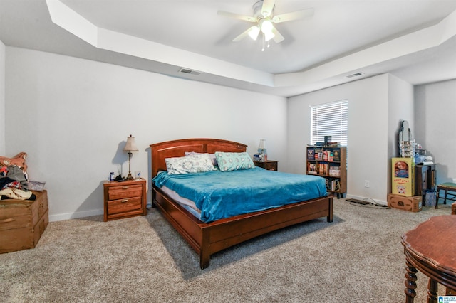 carpeted bedroom with ceiling fan and a raised ceiling