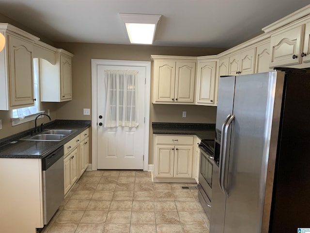 kitchen with sink, stainless steel appliances, light tile patterned floors, and cream cabinets