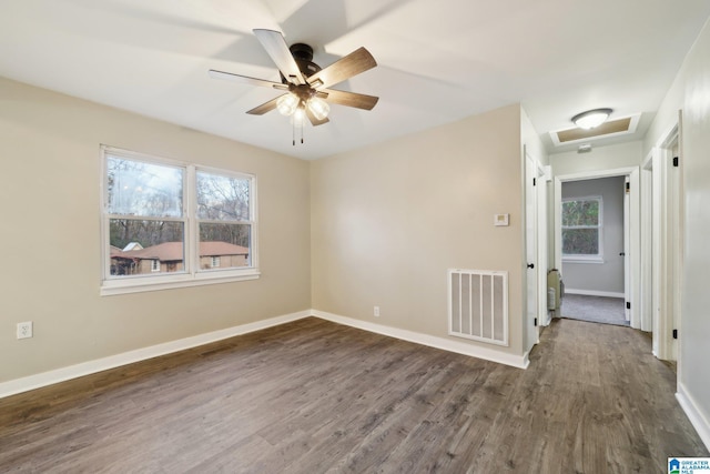 empty room featuring a wealth of natural light, dark hardwood / wood-style flooring, and ceiling fan