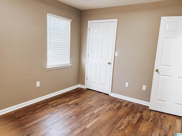 unfurnished bedroom with dark wood-type flooring