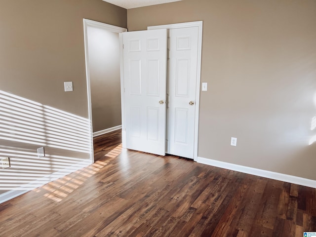 unfurnished bedroom with a closet and dark wood-type flooring