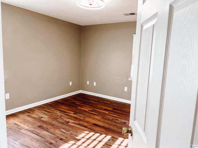 spare room with a textured ceiling and hardwood / wood-style flooring