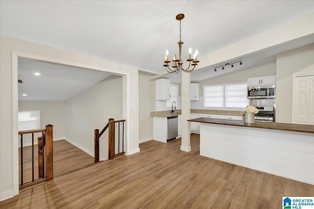 kitchen featuring decorative light fixtures, appliances with stainless steel finishes, plenty of natural light, and white cabinetry