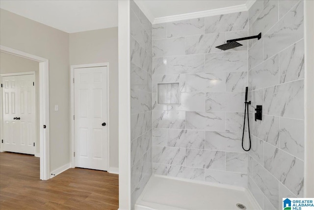 bathroom with hardwood / wood-style flooring, ornamental molding, and a tile shower