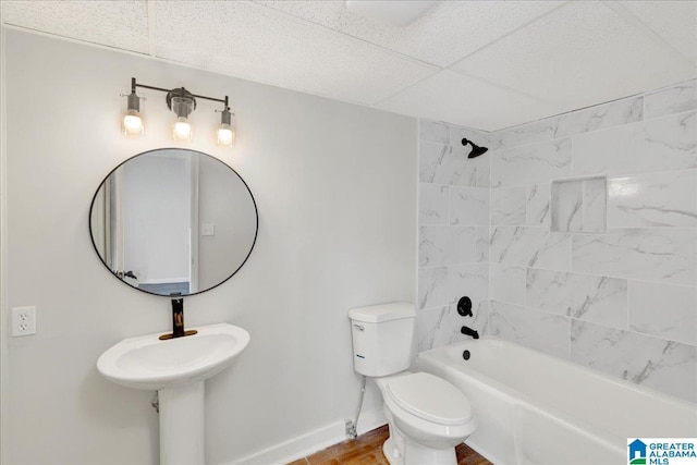 bathroom with toilet, a paneled ceiling, and tiled shower / bath