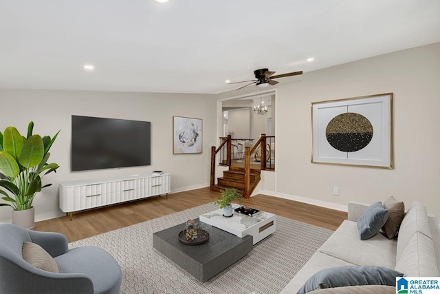 living room featuring lofted ceiling, ceiling fan with notable chandelier, and wood-type flooring