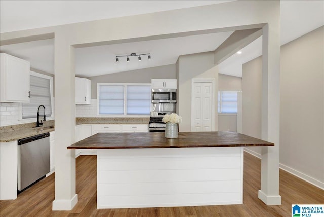 kitchen featuring backsplash, vaulted ceiling, butcher block counters, and stainless steel appliances