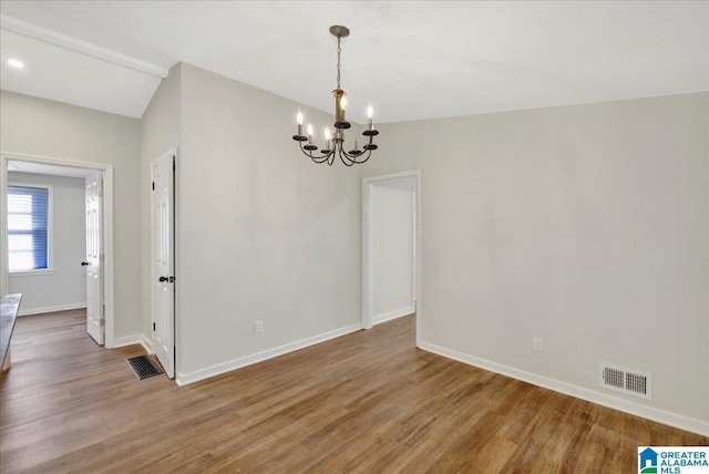 unfurnished room with wood-type flooring, a notable chandelier, and vaulted ceiling