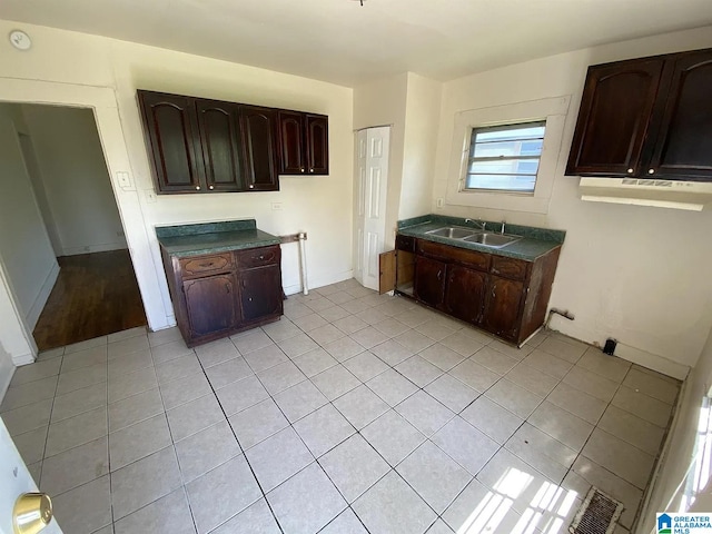 kitchen with light tile patterned flooring, dark brown cabinetry, and sink