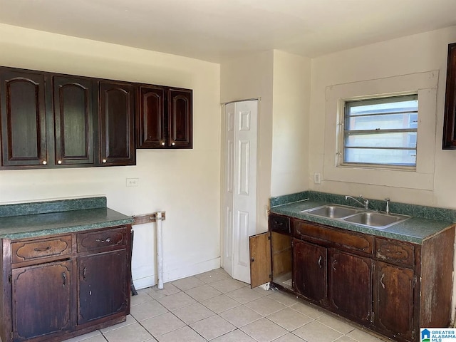 kitchen with dark brown cabinetry, sink, and light tile patterned floors