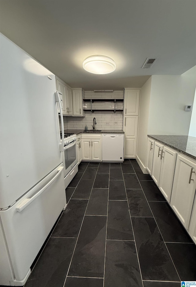 kitchen with sink, backsplash, dark stone counters, white appliances, and white cabinets