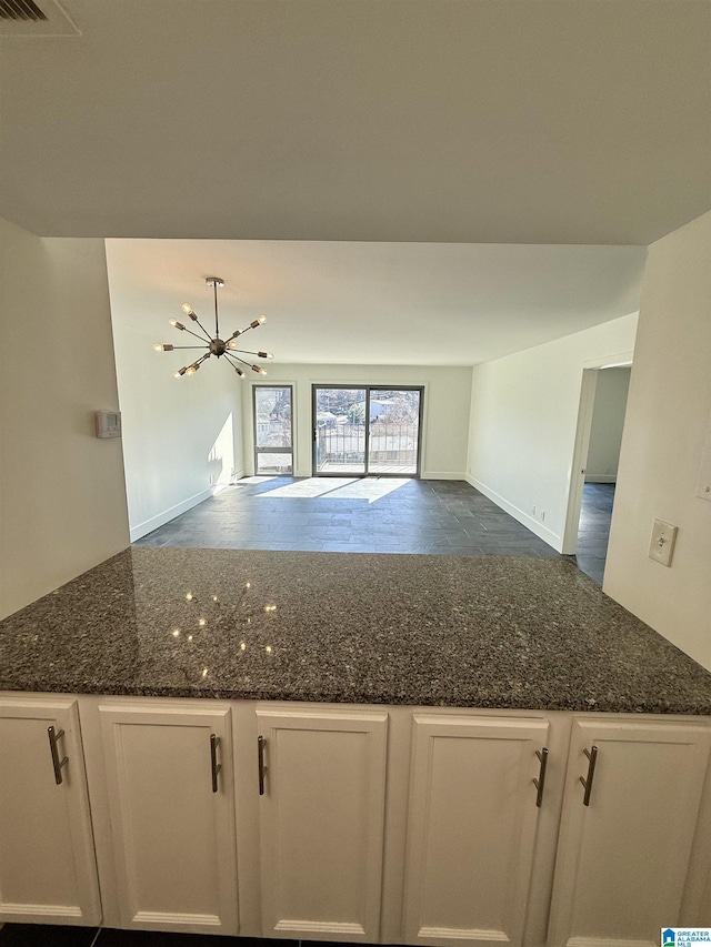 kitchen featuring white cabinetry, dark stone counters, and an inviting chandelier