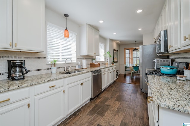 kitchen with dark hardwood / wood-style flooring, white cabinets, stainless steel appliances, and decorative light fixtures