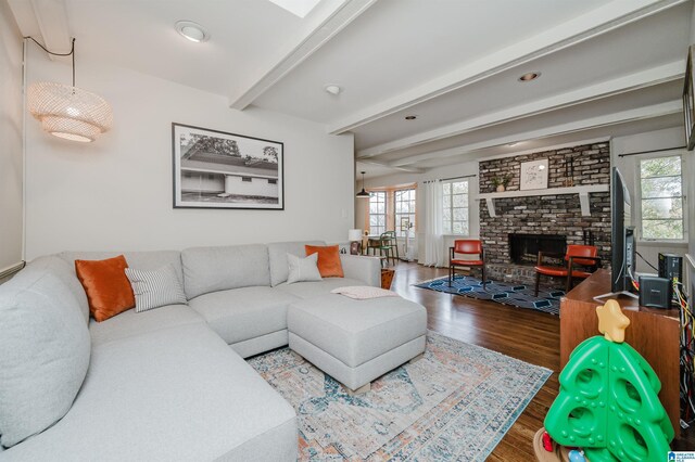 living room with hardwood / wood-style floors, beam ceiling, and a brick fireplace