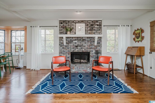 living area with hardwood / wood-style floors, beam ceiling, and a fireplace