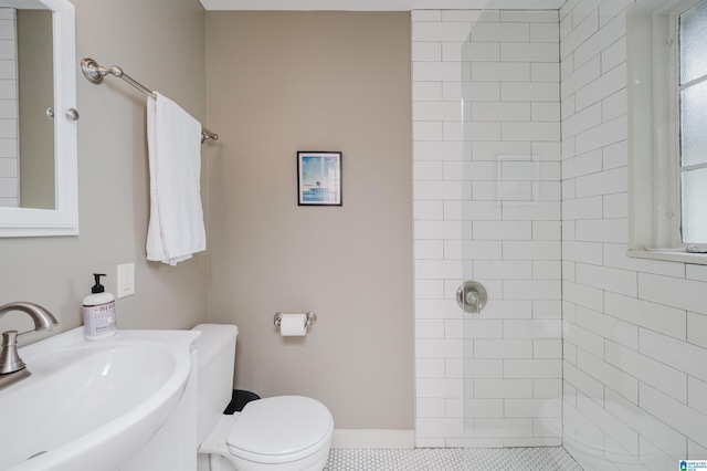 bathroom with a tile shower, toilet, tile patterned floors, and sink