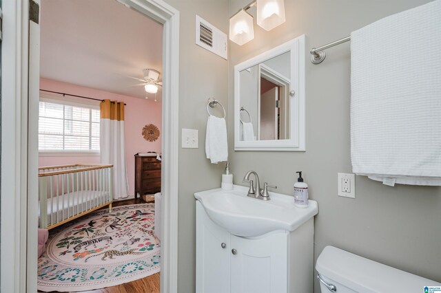 bathroom featuring vanity, hardwood / wood-style flooring, toilet, and ceiling fan