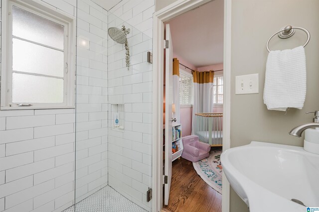 bathroom featuring a tile shower, sink, and wood-type flooring