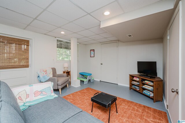 living room featuring a paneled ceiling and concrete floors