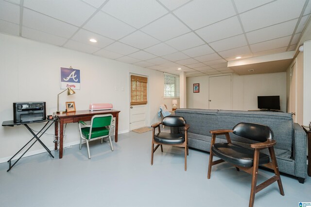 living area featuring a drop ceiling and concrete floors