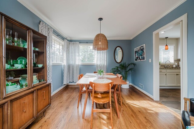 dining space with light hardwood / wood-style floors, ornamental molding, and a wealth of natural light