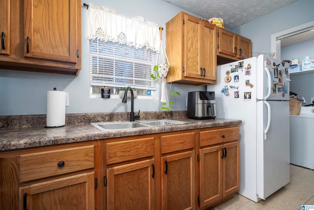 kitchen with sink, white refrigerator, a textured ceiling, washer / dryer, and light tile patterned flooring