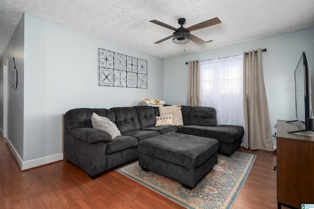 living room featuring ceiling fan, wood-type flooring, and a textured ceiling