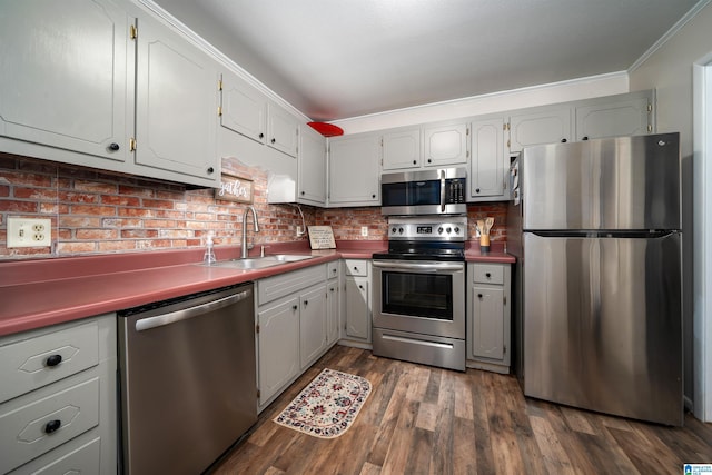 kitchen featuring dark wood-type flooring, sink, crown molding, decorative backsplash, and stainless steel appliances