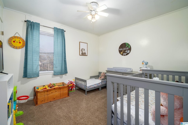 bedroom with carpet flooring, ceiling fan, ornamental molding, and a nursery area