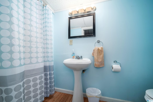 bathroom with curtained shower, sink, a textured ceiling, toilet, and hardwood / wood-style flooring