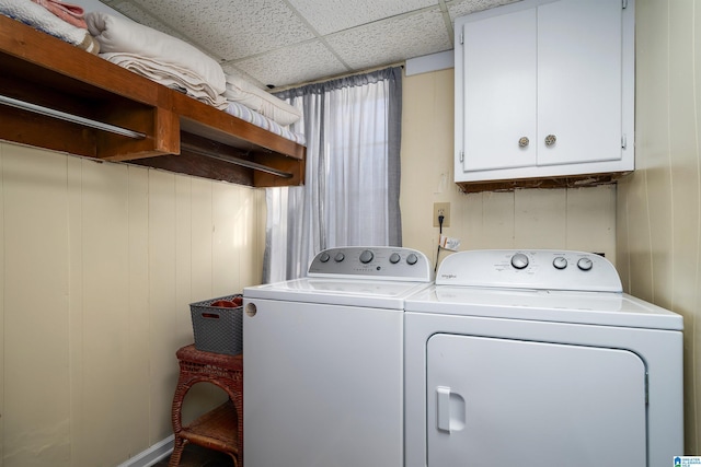 washroom with cabinets, wooden walls, and washing machine and clothes dryer