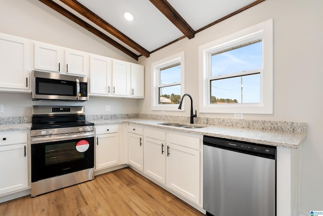 kitchen with appliances with stainless steel finishes, sink, lofted ceiling with beams, light hardwood / wood-style flooring, and white cabinetry