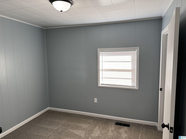 empty room with wood walls and carpet