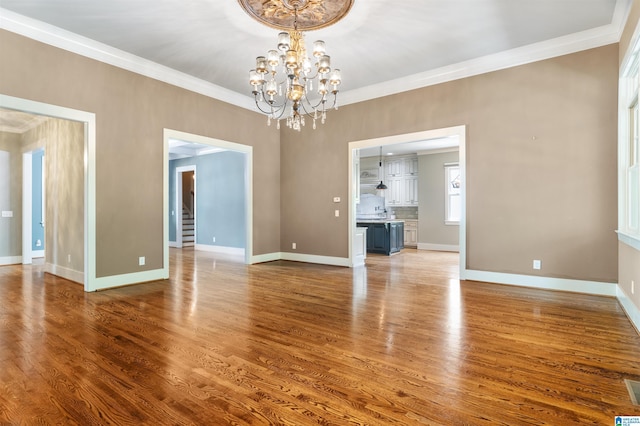 unfurnished dining area featuring hardwood / wood-style flooring, a notable chandelier, and ornamental molding