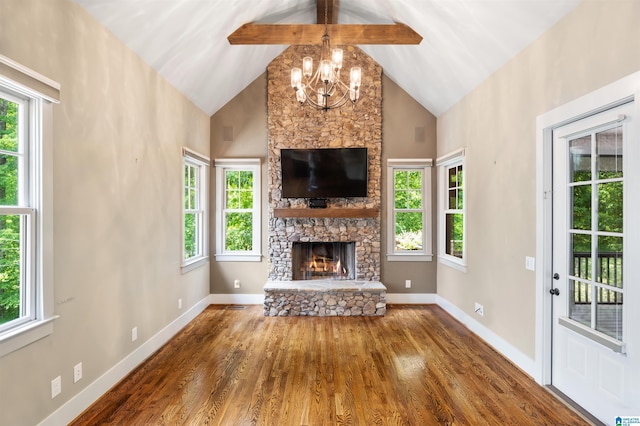 unfurnished living room with beamed ceiling, a fireplace, a wealth of natural light, and a chandelier