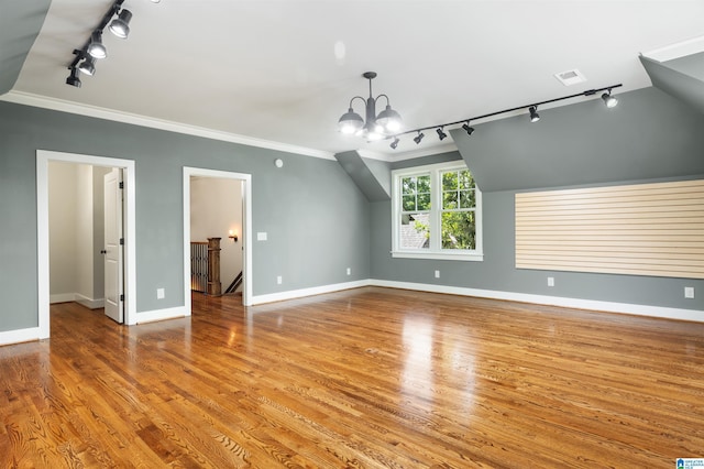 interior space featuring light hardwood / wood-style floors, vaulted ceiling, ornamental molding, and a notable chandelier