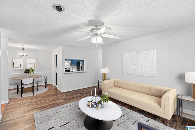 living room with wood-type flooring, ceiling fan with notable chandelier, and a textured ceiling