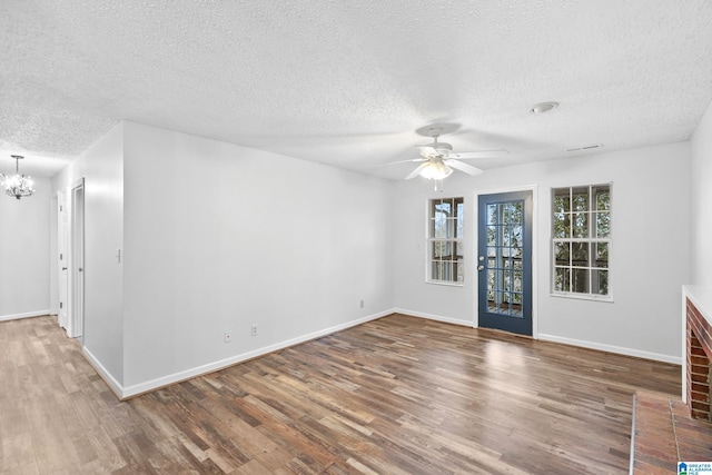 unfurnished room featuring a textured ceiling, wood-type flooring, and ceiling fan with notable chandelier