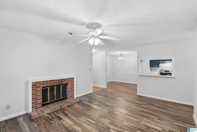 unfurnished living room with a textured ceiling, a fireplace, dark hardwood / wood-style floors, and ceiling fan with notable chandelier