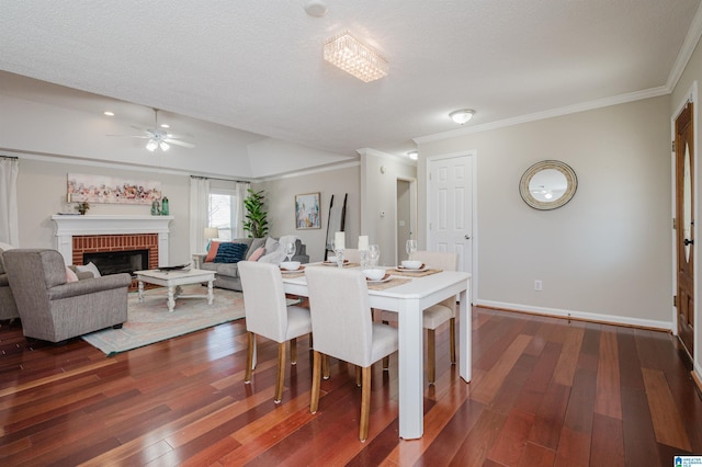 dining room with ceiling fan, dark hardwood / wood-style flooring, a textured ceiling, and a brick fireplace